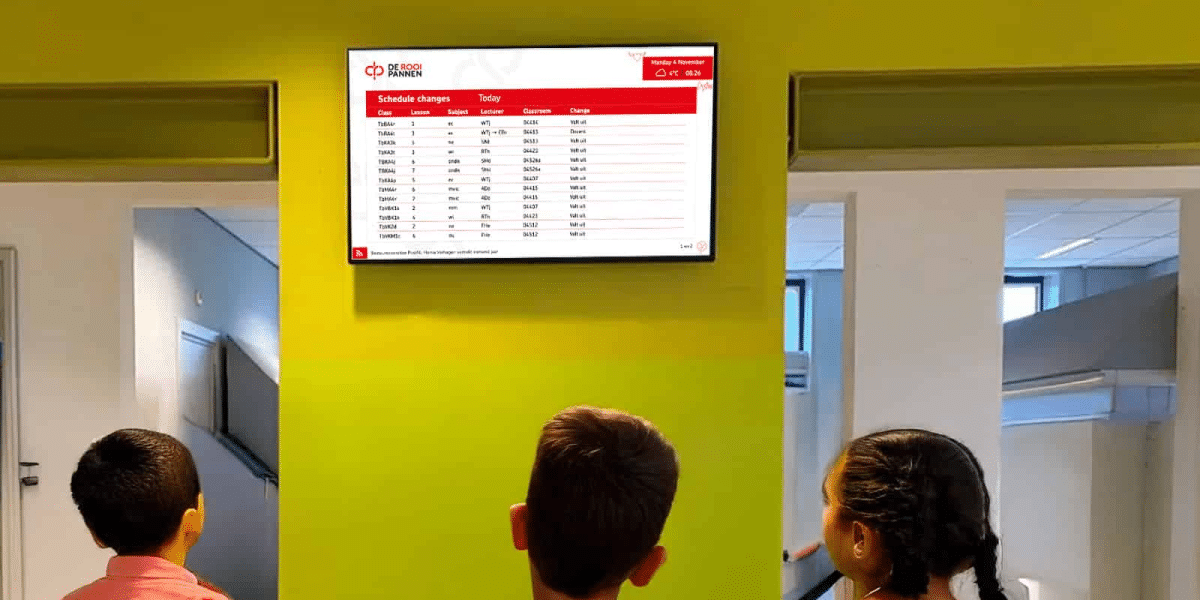 Monteur plaatst digitaal informatiescherm in de schoolgang