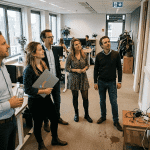 Een team op kantoor bekijkt samen het digitale informatiescherm.